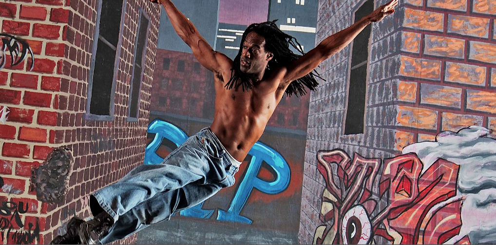 Darryl Thomas, Artistic Director, mid-leap in a dynamic dance pose